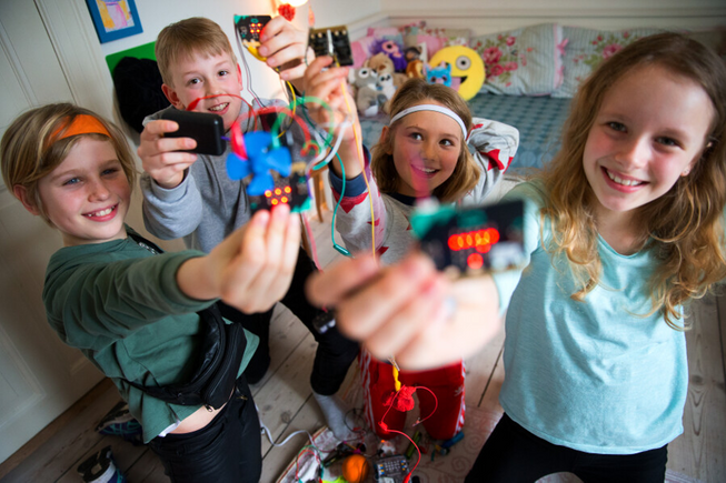 Four children smiling holding up micro:bits