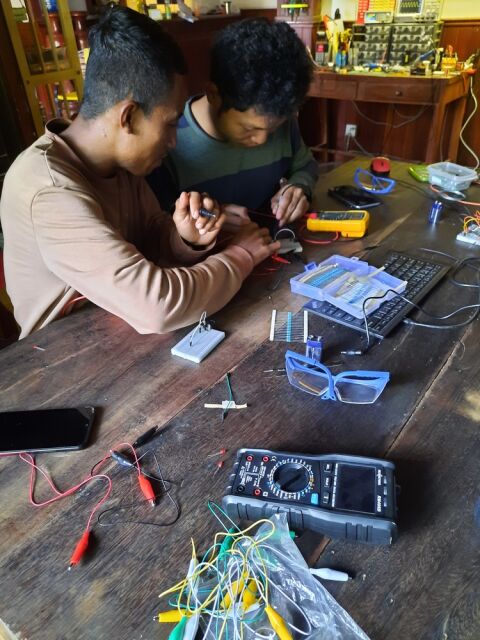 Two students exploring their circuit using a multi-meter in the class
